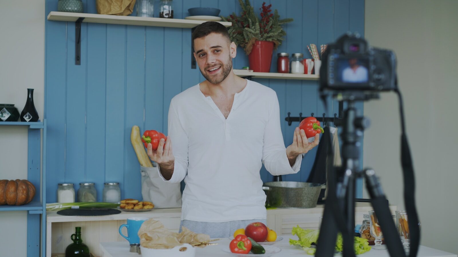 Man holding red peppers in a kitchen.