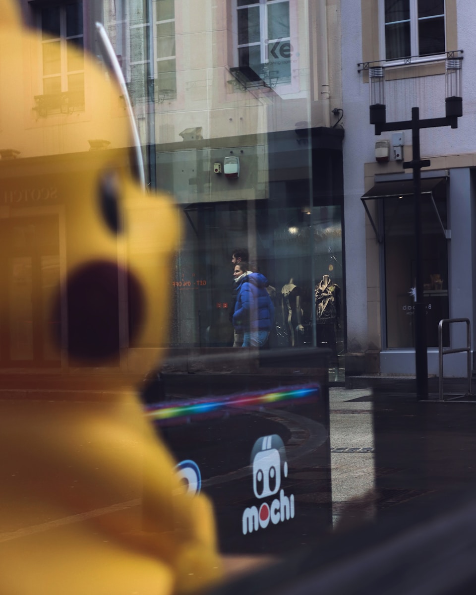 A large yellow stuffed animal sitting in front of a store window